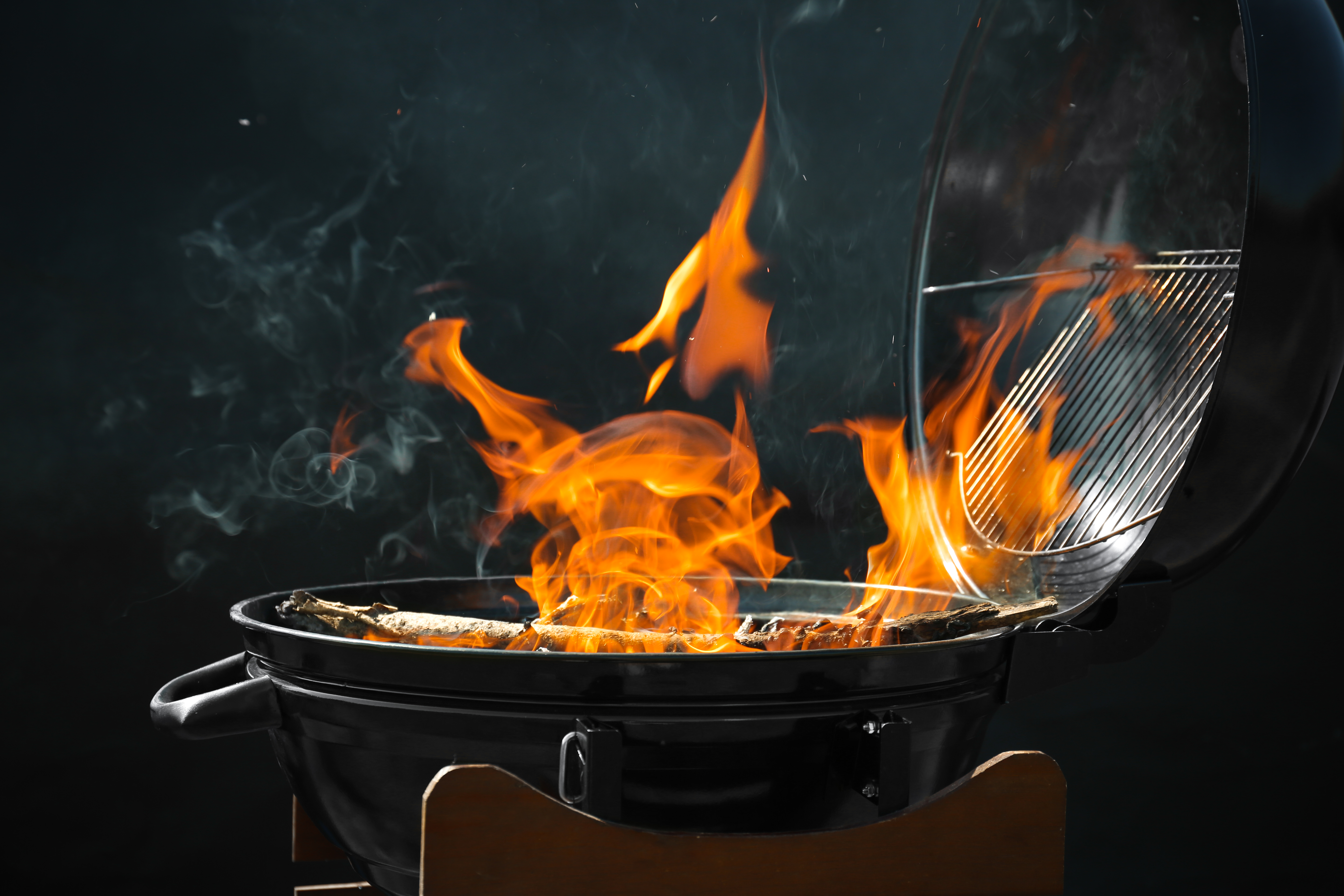 New modern barbecue grill with burning firewood on dark background